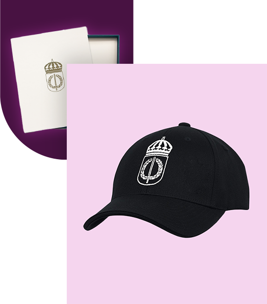 Svart keps med F&ouml;rsvarsh&ouml;gskolans vita logotyp. Guldlogotyp p&aring; vitt papper baktill.