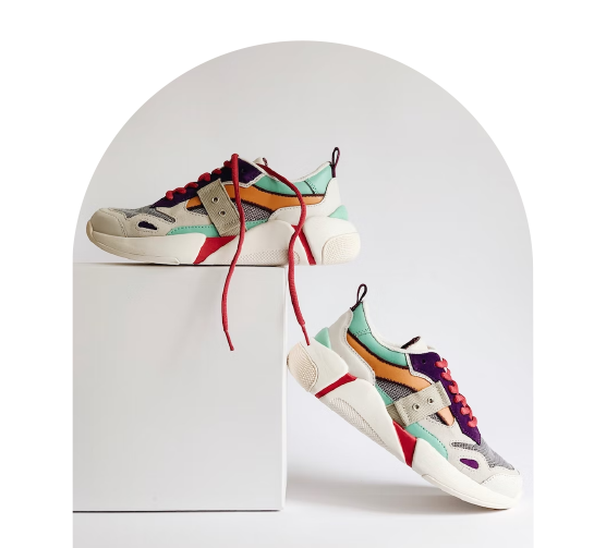 F&auml;rgglada sneakers med r&ouml;da skosn&ouml;ren, placerade p&aring; och bredvid en vit piedestal